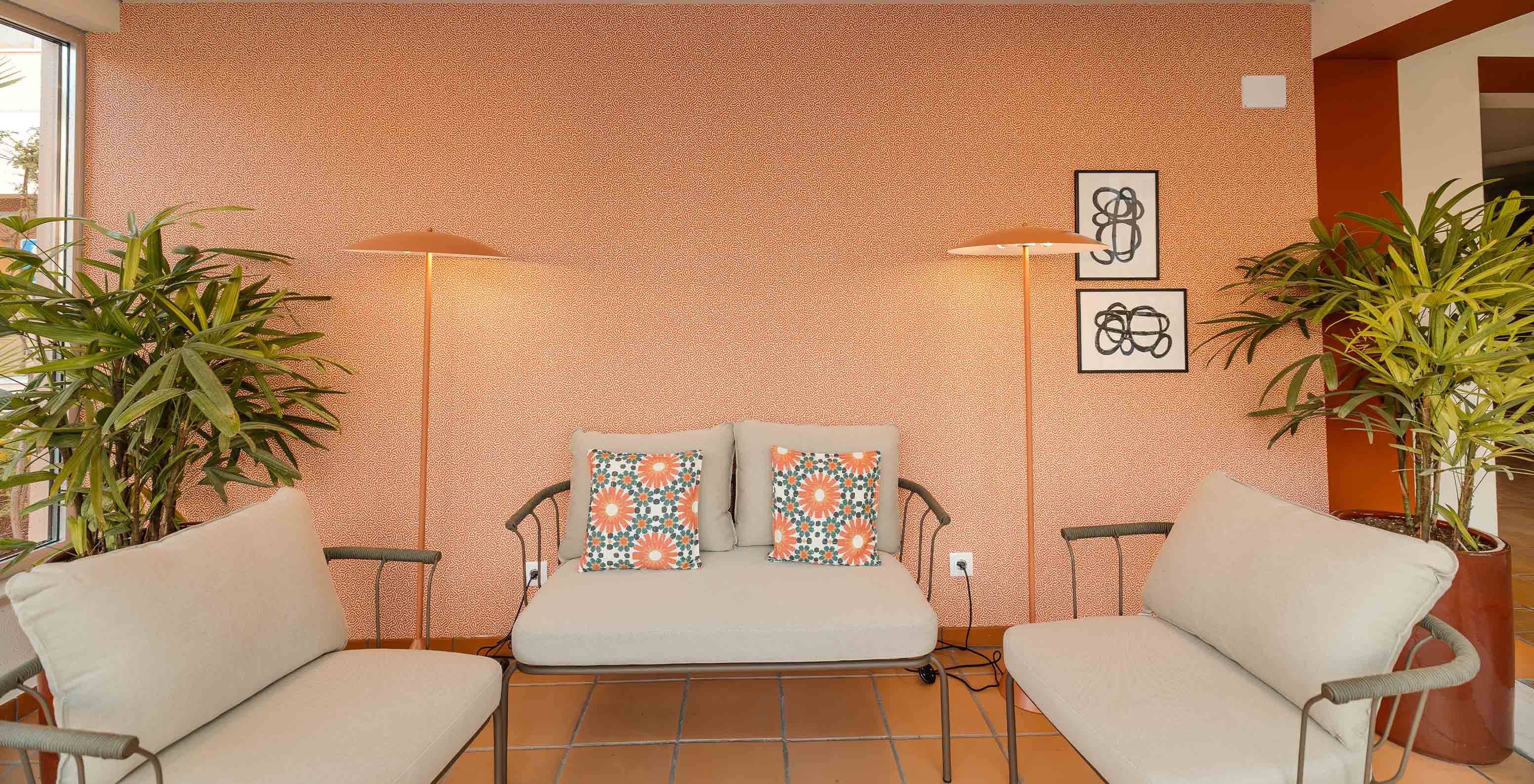 Hall del hotel cerca de la playa con piscina, papel naranja, tres sofás beige cómodos y decoración acogedora