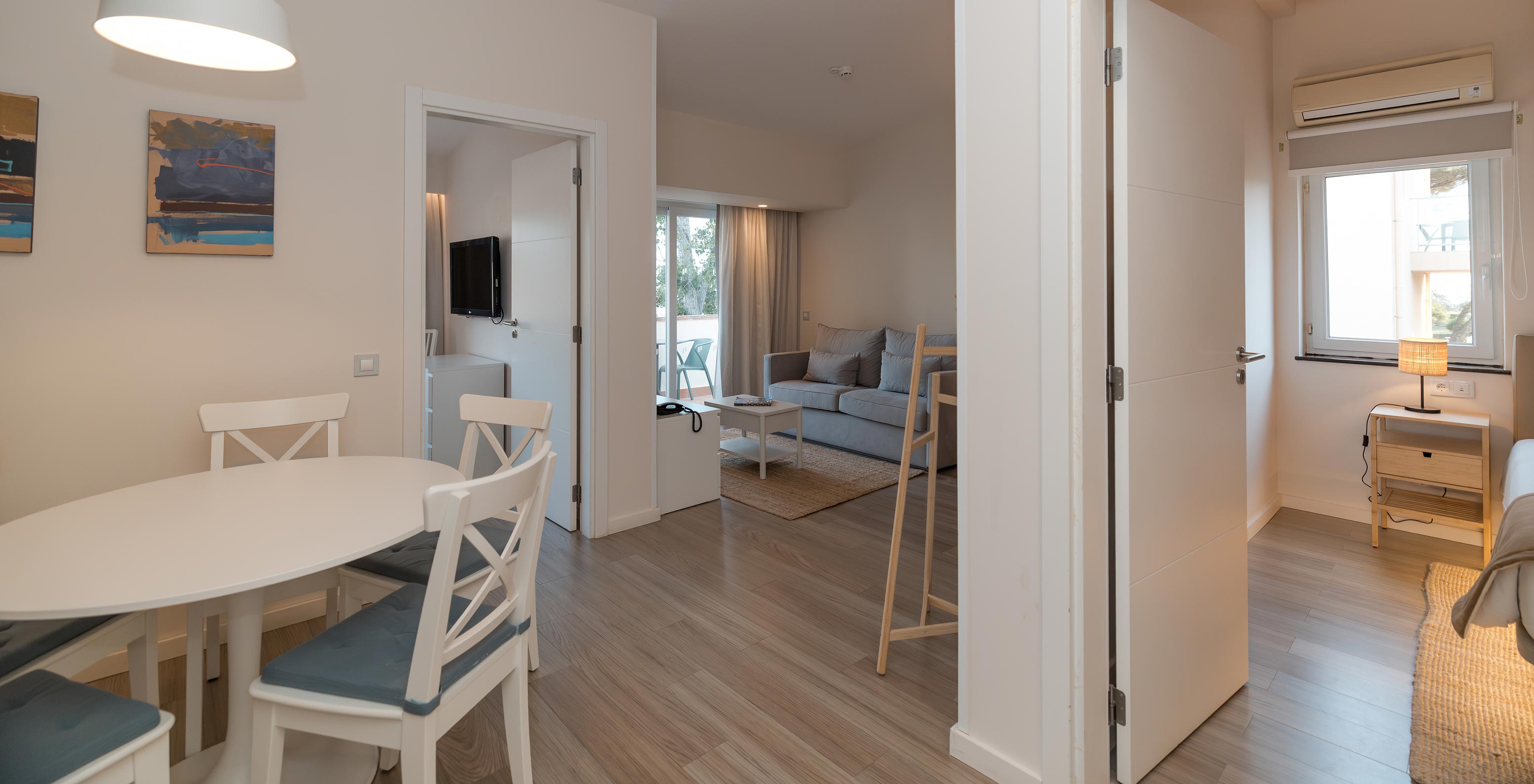 Villa 2 Habitaciones Vista Jardín en Pestana Alvor Beach Villas tiene sala con sofá, mesa de comedor y dos habitaciones