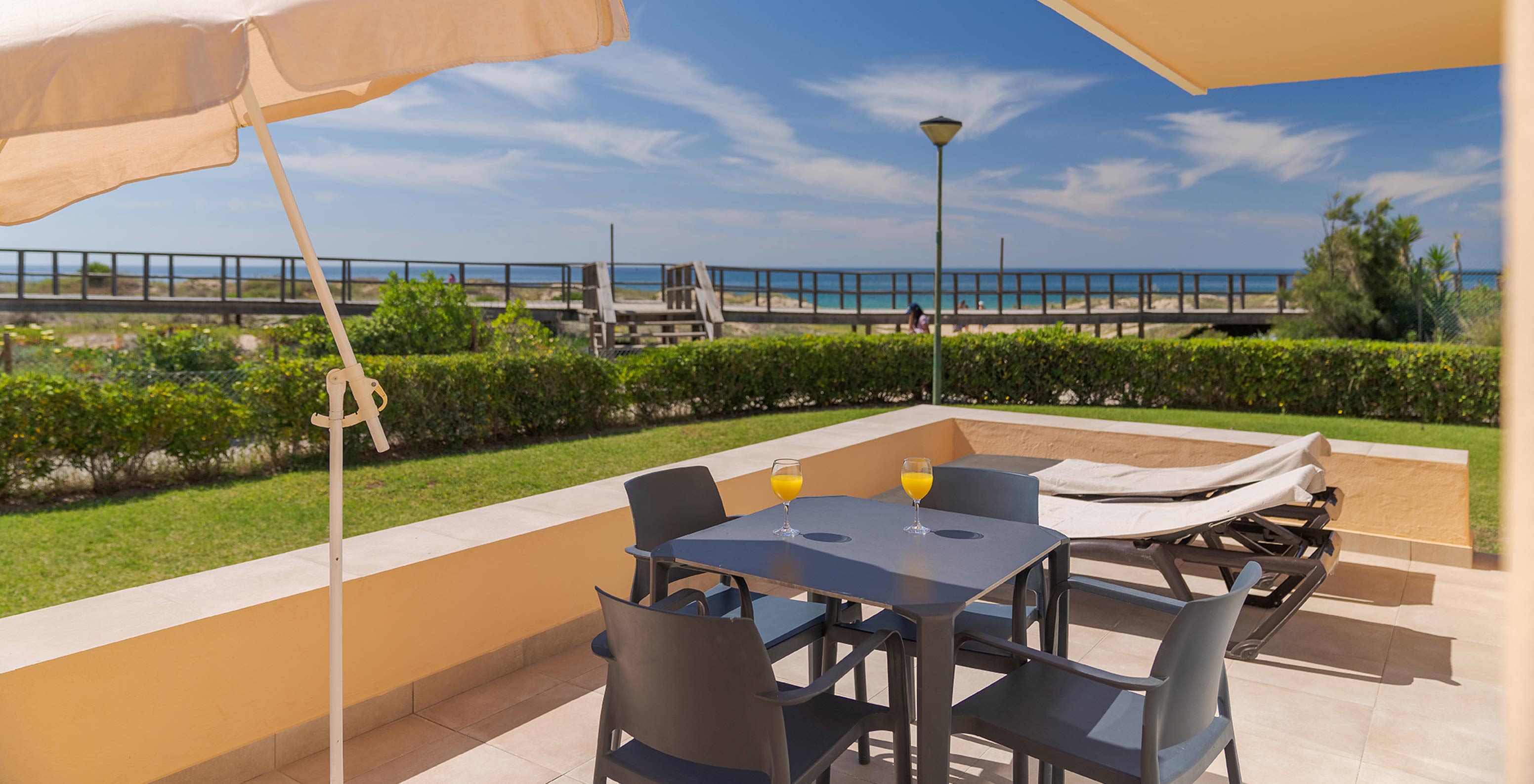 La Villa Premium de 2 Dormitorios con Vista al Jardín en Pestana Alvor Beach Villas tiene un balcón con una mesa y tumbonas