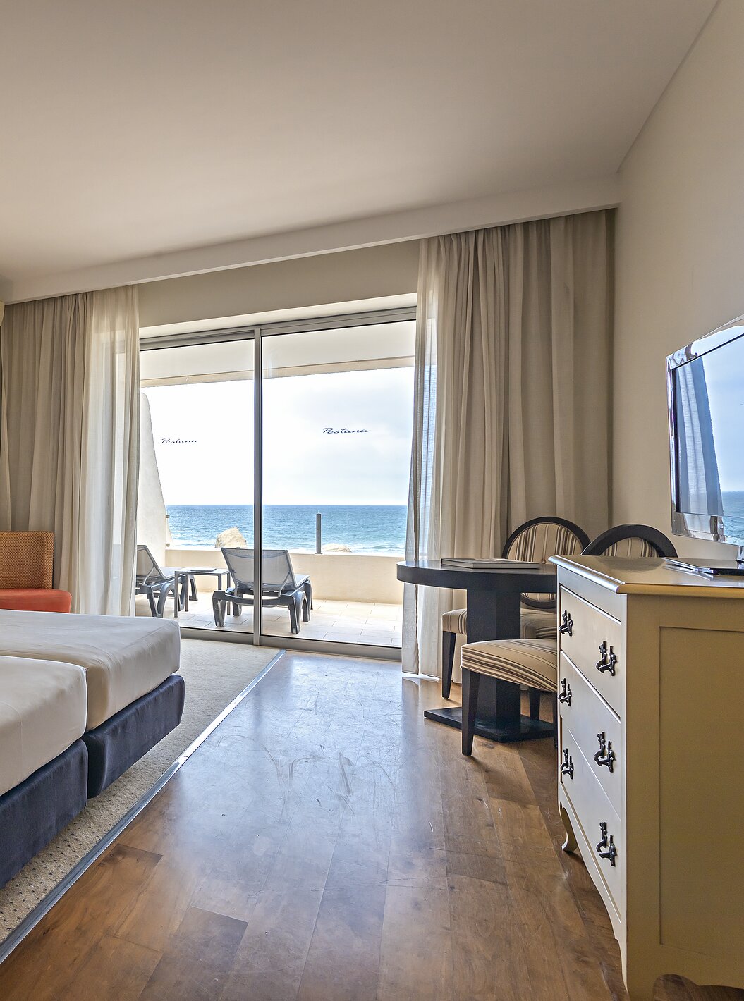 La Suite Cliff T1 en Pestana Alvor Praia tiene un dormitorio doble con un balcón con tumbonas y vistas al mar
