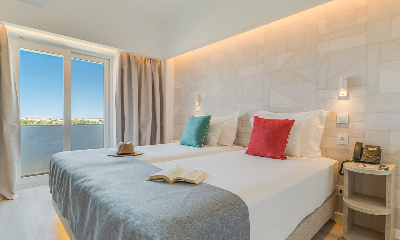 El Cuarto Clásico Vista Jardín del Pestana Blue Alvor Beach tiene dos camas con sábanas blancas y almohadas coloridas