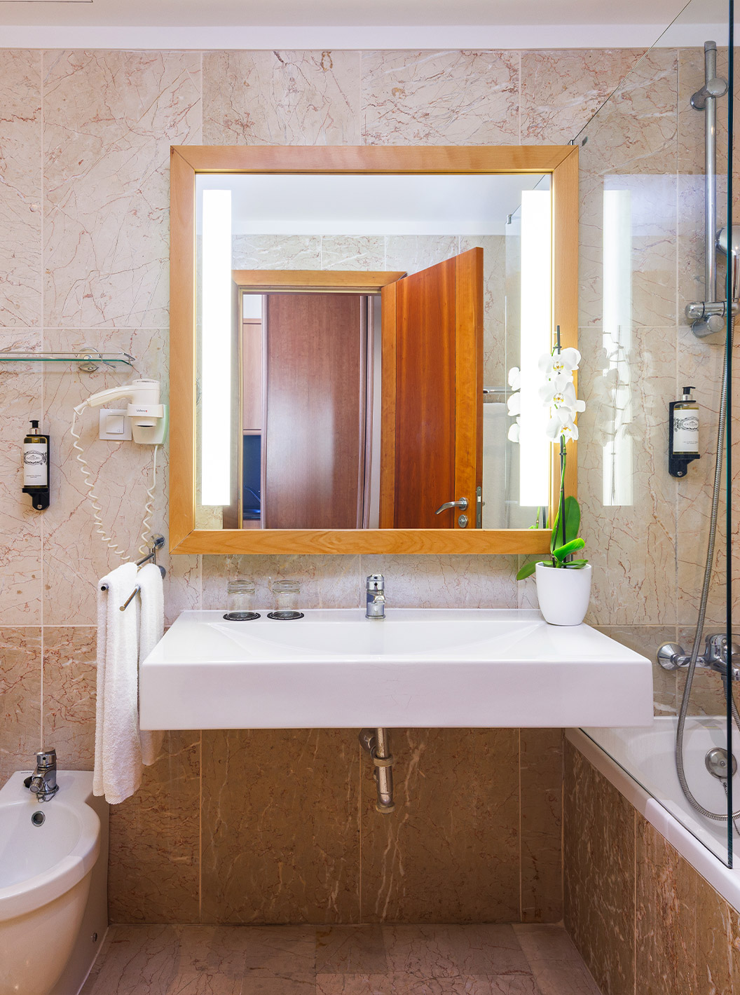 Habitación Deluxe Vista Mar en Pestana Viking, baño con espejo iluminado, lavabo blanco y paredes de mármol