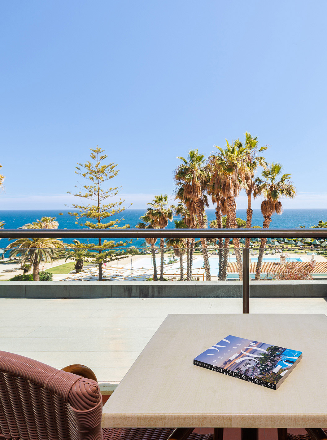 Suite con Vista al Mar de Pestana Viking, balcón con mesa y sillones frente a palmeras y el océano
