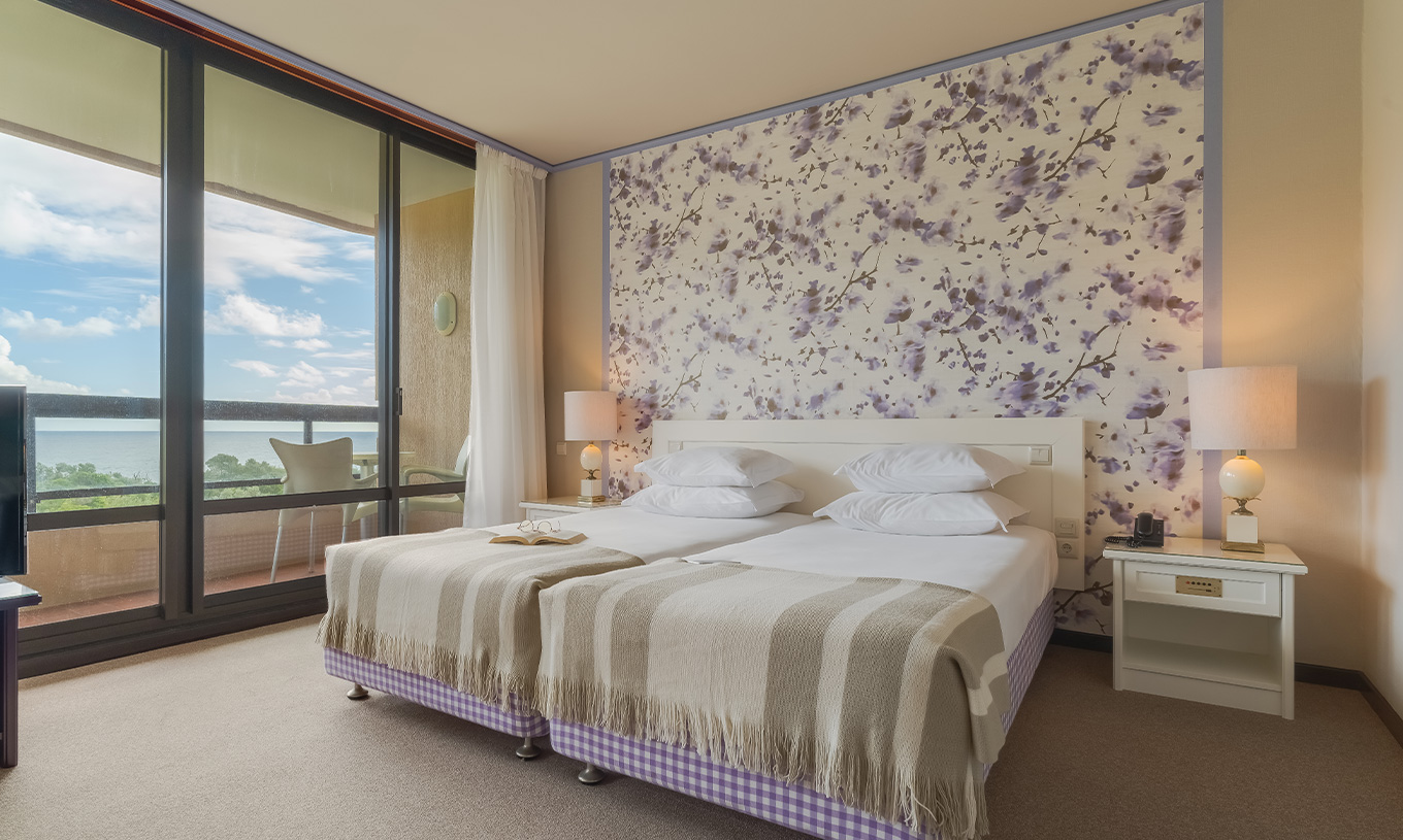 En la Junior Suite Vista Jardín del Pestana Bahia Praia, las camas están al lado del balcón con vista a jardines y al mar