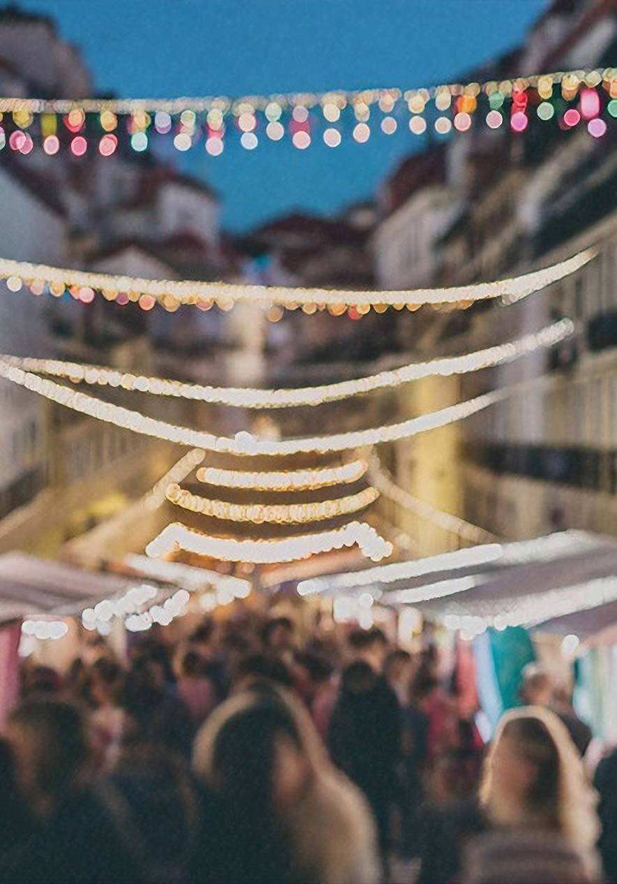 Festival de Santo Antonio en Lisboa con guirnaldas iluminadas y visitantes entre puestos al anochecer