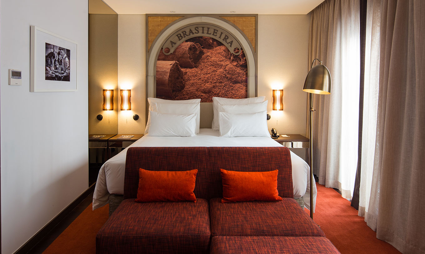 Habitación Clásica Blend en Pestana Porto - A Brasileira con cama doble, sillones rojos y lámparas cálidas