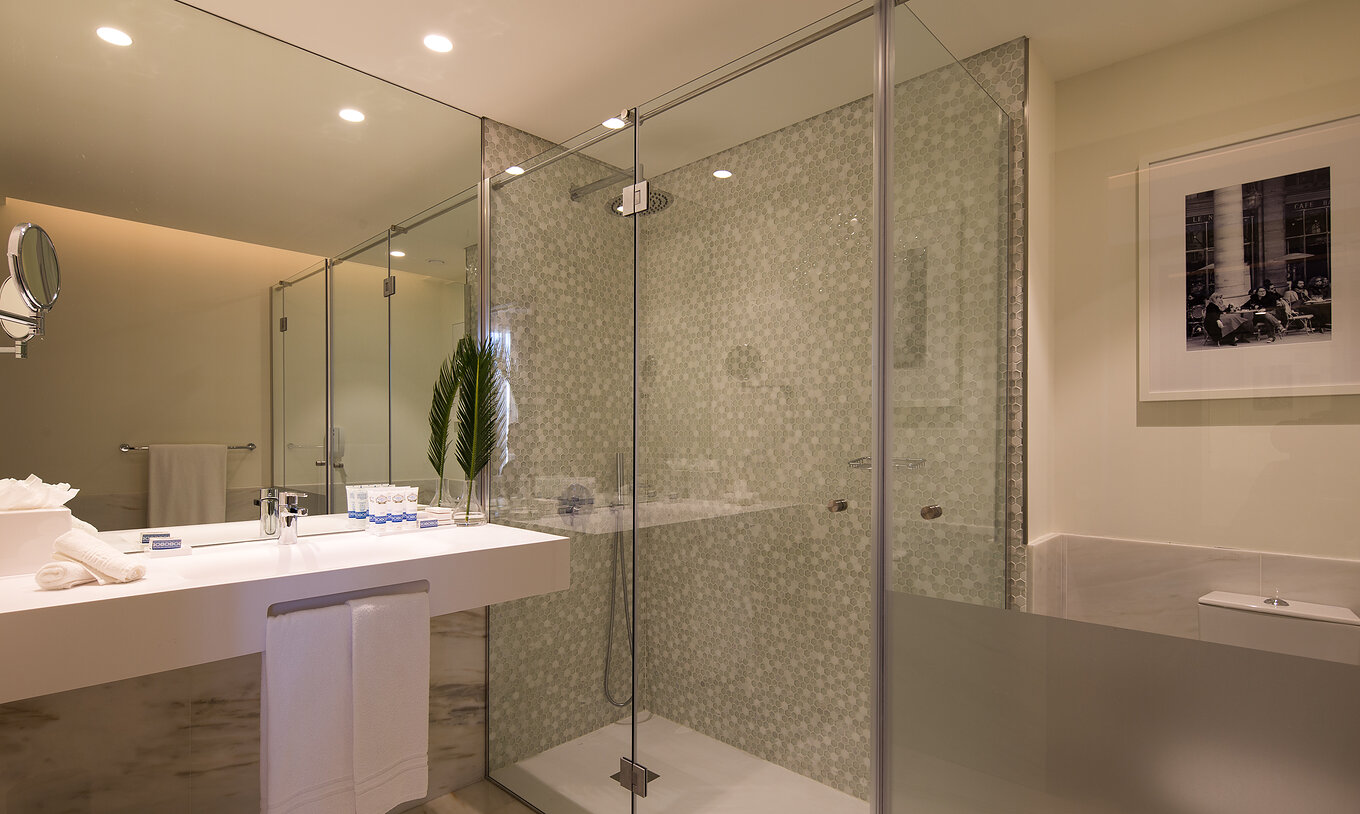 El Deluxe Executive Grand View del Pestana Porto - A Brasileira tiene una bañera grande con ducha con azulejos hexagonales La Master Suite del Pestana Porto - A Brasileira tiene un baño con ducha y un lavabo grande