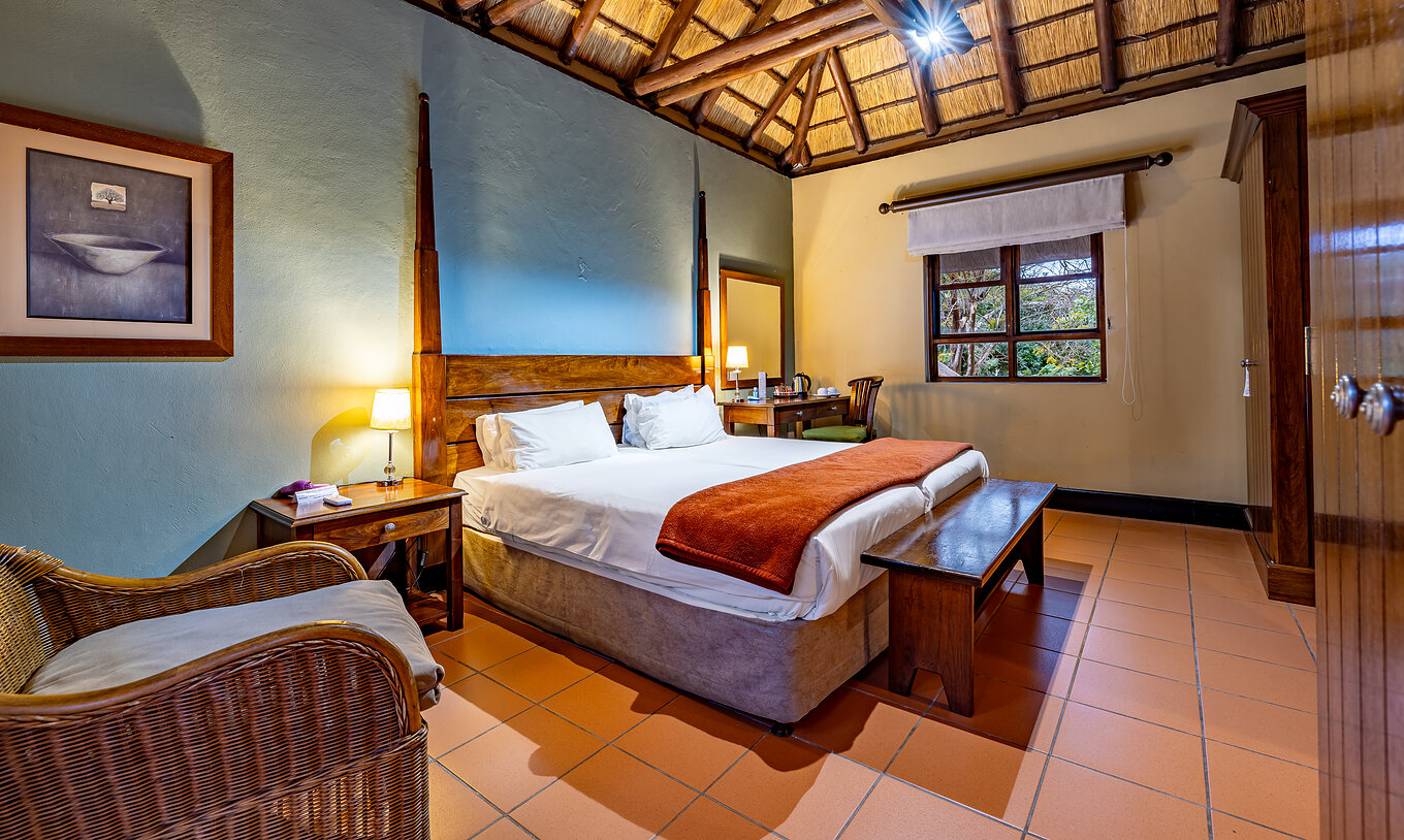 El Quarto Clássico del Pestana Kruger Lodge tiene dos camas individuales, una silla y tiene una decoración con madera