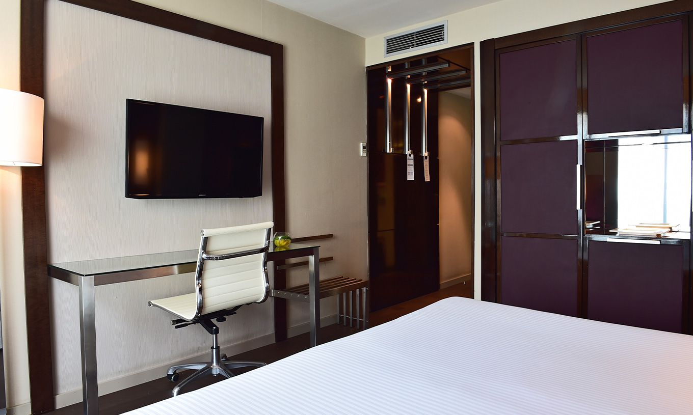 El cuarto Premium del Pestana Arena Barcelona tiene televisión al pie de la cama y armario en tono púrpura