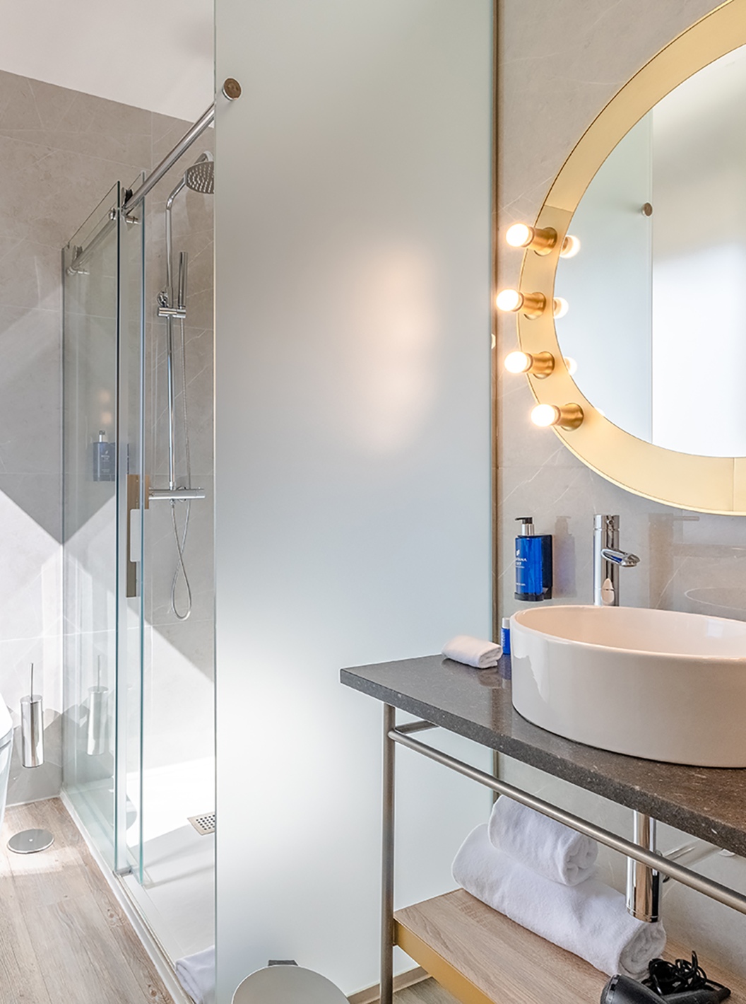 La Habitación Doble Pequeña del Pestana CR7 Gran Vía Madrid tiene un baño con un espejo redondo, inodoro y ducha