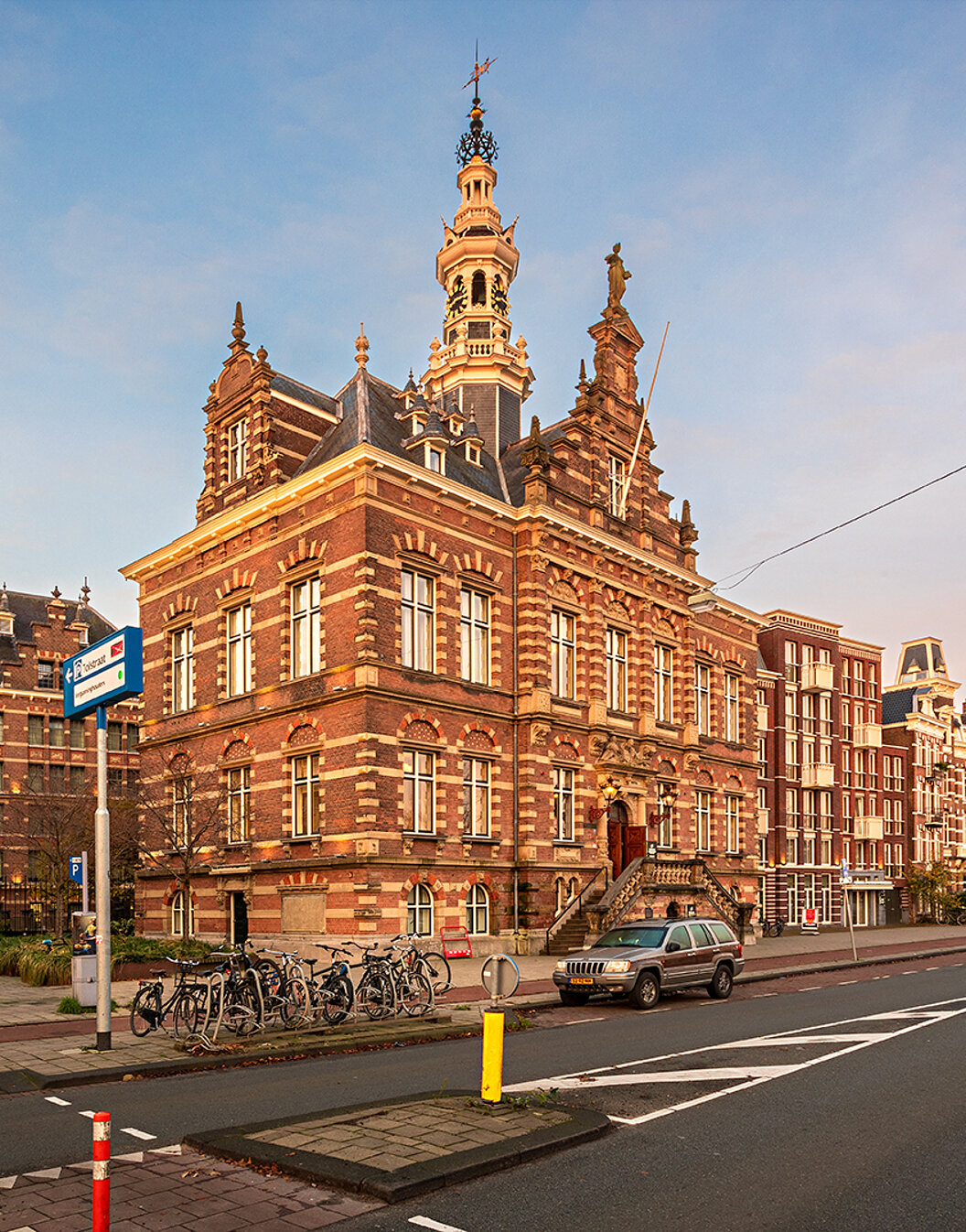 Vista exterior de Pestana Amsterdam Riverside, con ladrillos rojos, bicicletas estacionadas y cielo claro
