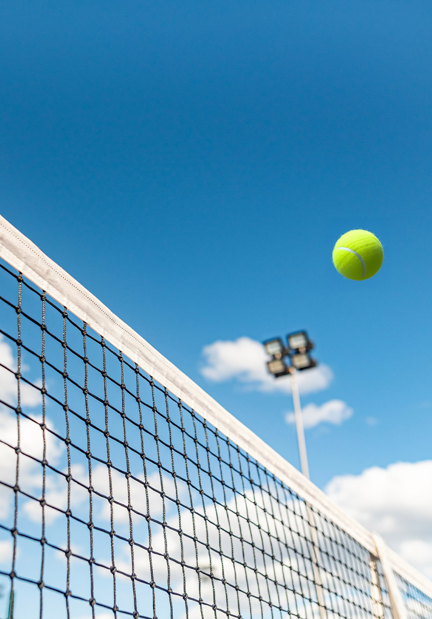 Partido de tenis en Wimbledon con pelota sobre la red y cielo despejado como actividad cerca del hotel