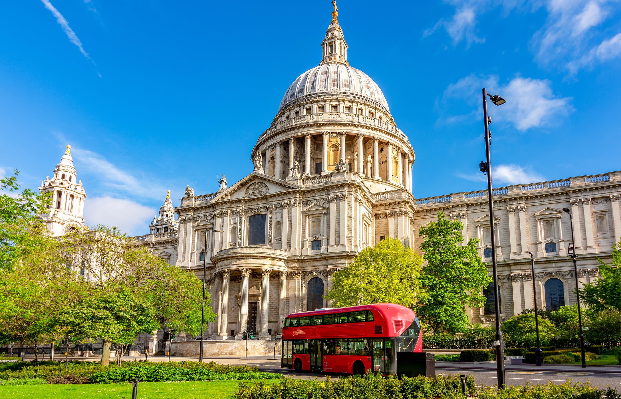 Vista urbana de la Catedral de San Pablo en Londres, con un autobús rojo enfrente y un jardín