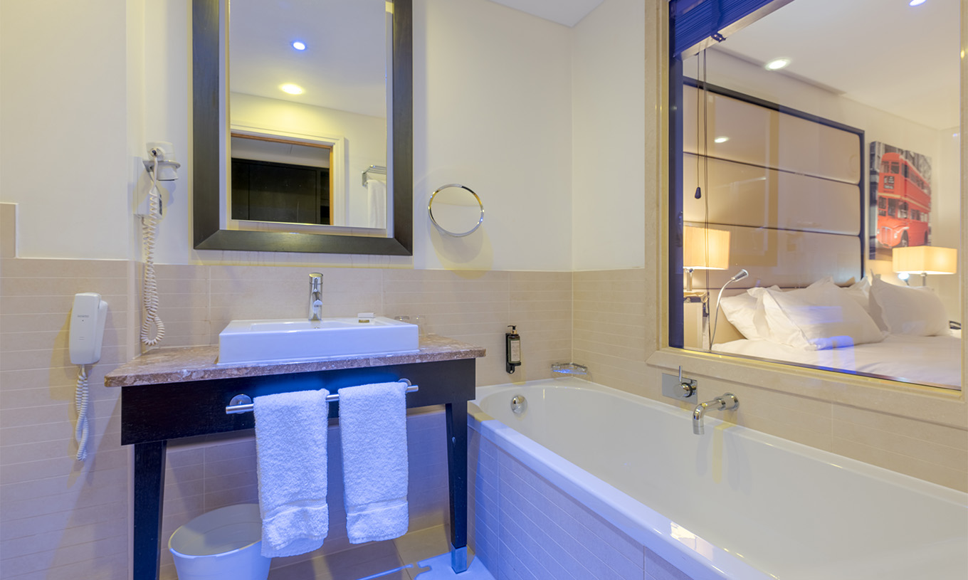 El Deluxe Superior King del Pestana Chelsea Bridge tiene baño con bañera, vidrio para el cuarto, lavabo y espejos