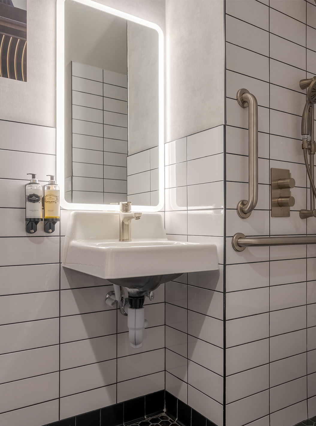 Habitación ADA Deluxe King en Pestana CR7 Times Square con baño accesible, lavabo iluminado y barras de apoyo