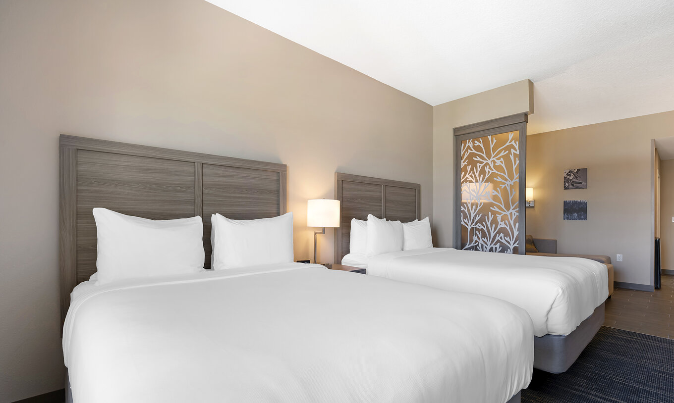 La Suite Doble Queen ADA del Pestana Orlando Suites Lake Buena Vista tiene dos camas y mesa de noche con lámpara