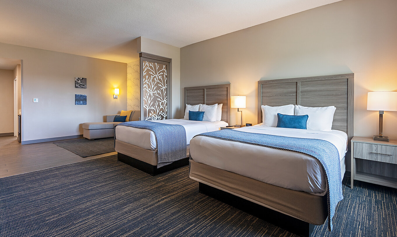 Master Suite Doble Queen en Pestana Orlando Suites Lake Buena Vista con dos camas, sofá y lámparas cálidas