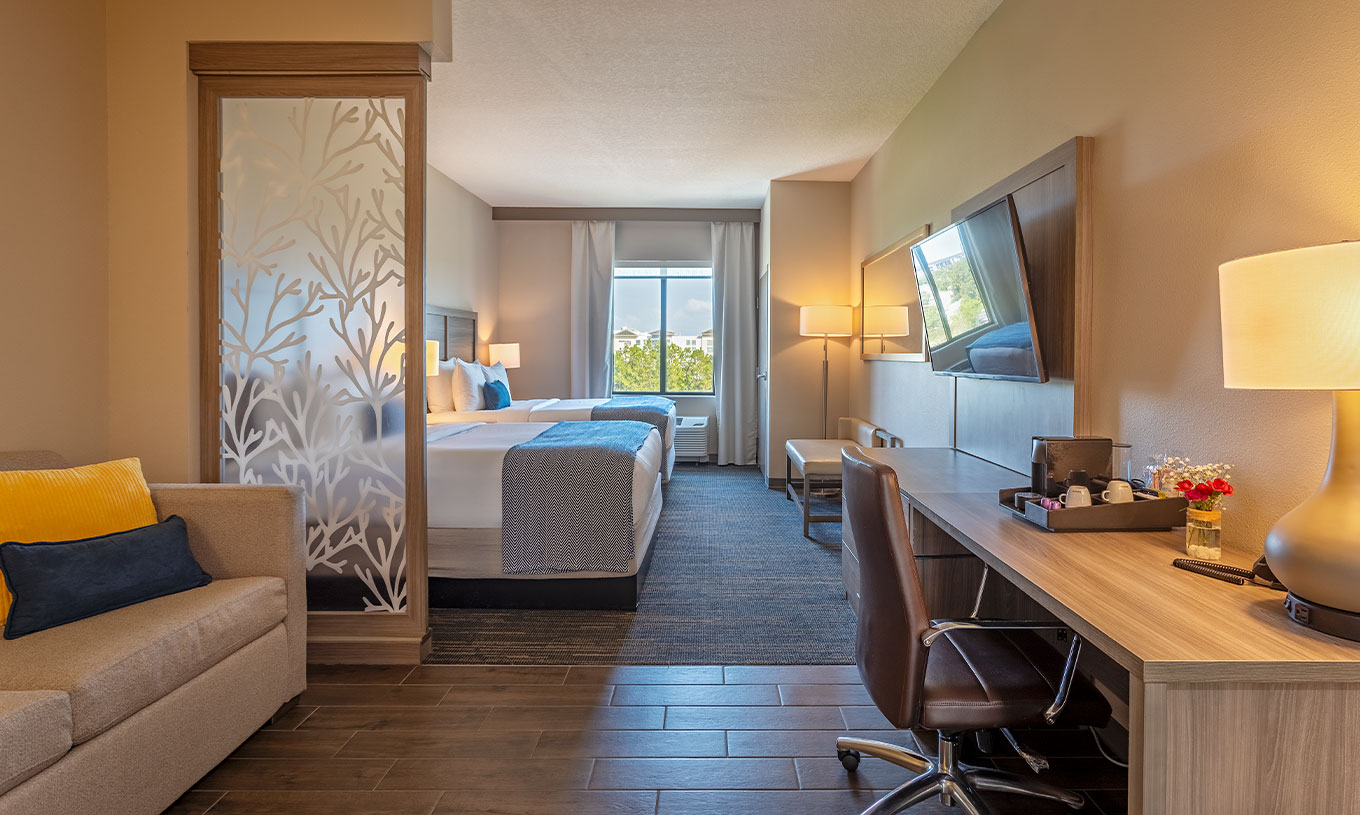 Suite Doble Queen Superior en Pestana Orlando Suites Lake Buena Vista, con escritorio y dos camas junto a ventana