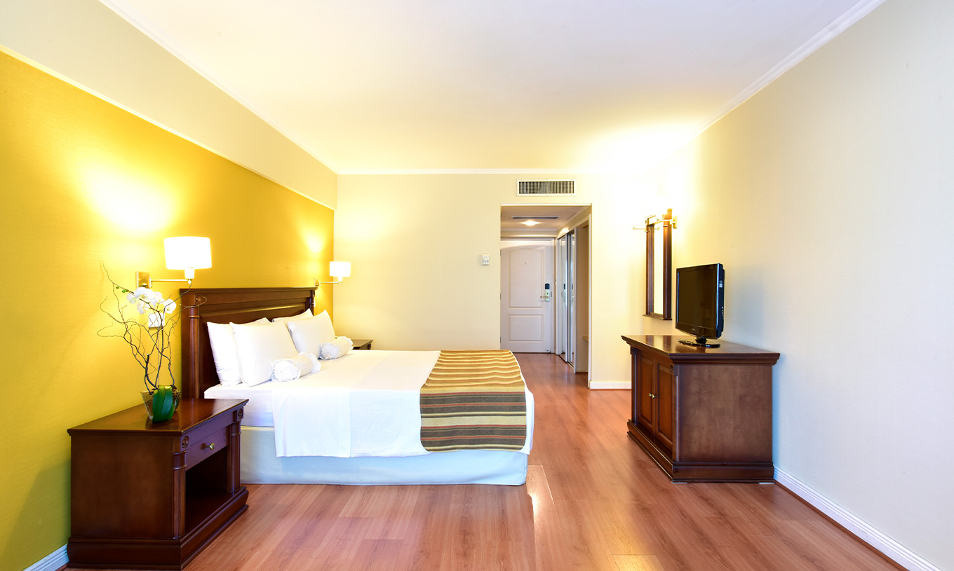 La habitación Queen Deluxe del Pestana Buenos Aires cuenta con una cama de matrimonio, televisión, espejo y mesita