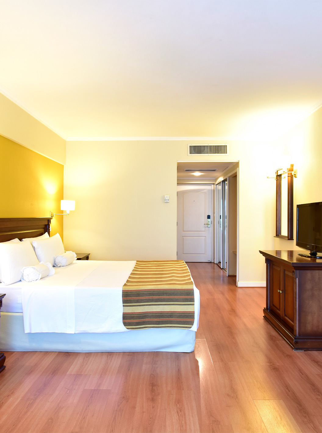 La habitación Queen Deluxe del Pestana Buenos Aires cuenta con una cama de matrimonio, televisión, espejo y mesita