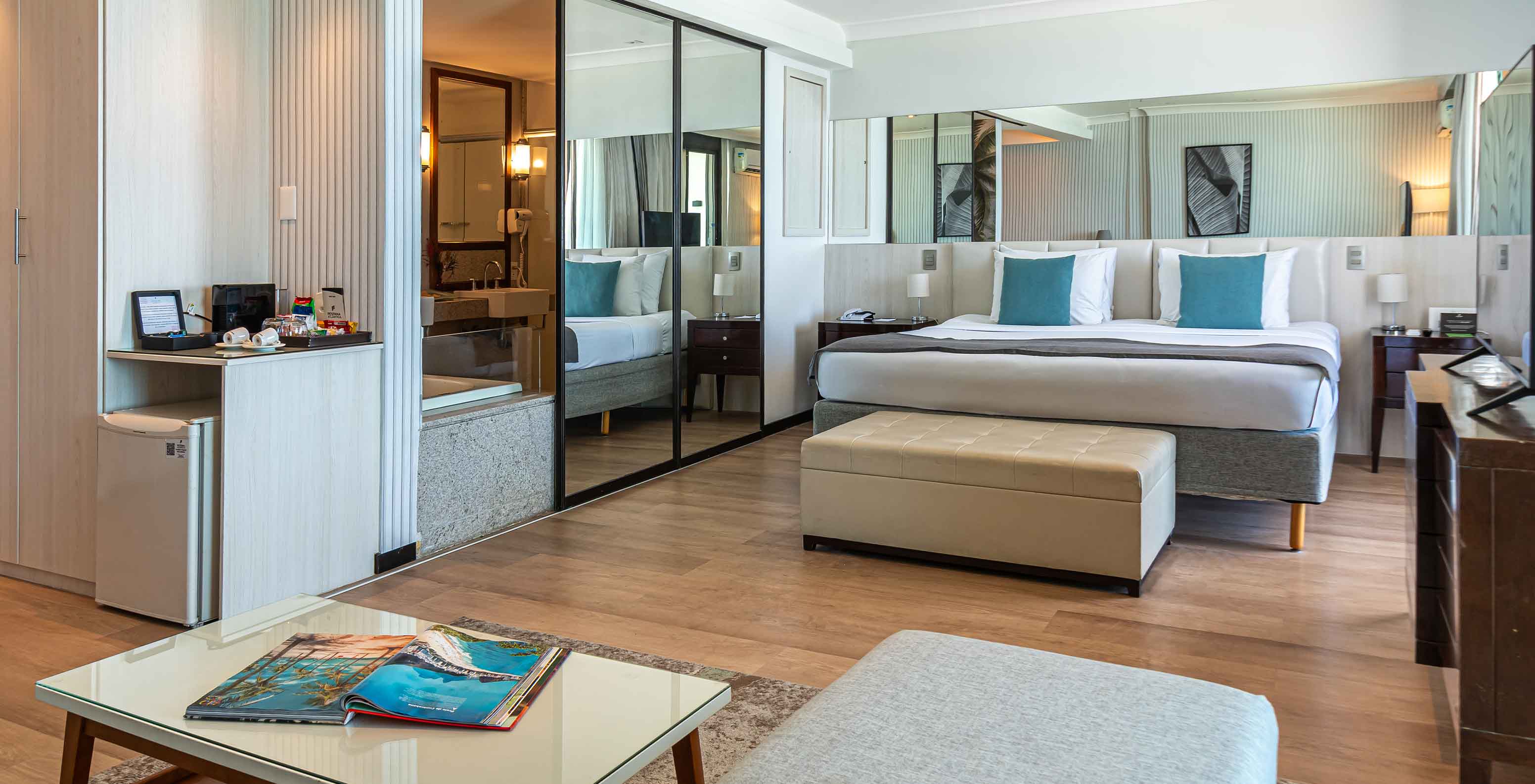 La Suite Oceánica del Pestana Rio Atlântica tiene cuarto moderno con cama, espejo y sala.