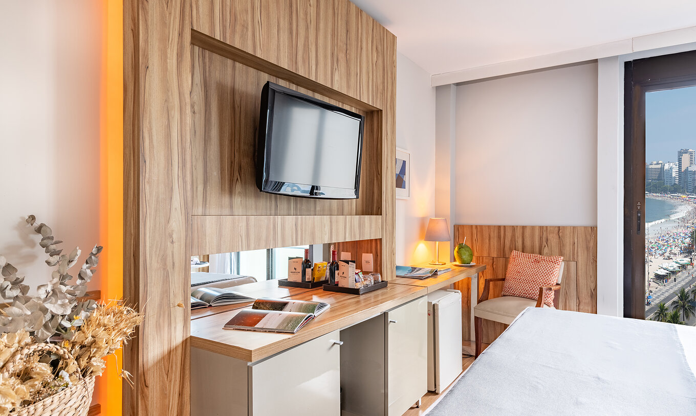 El Quarto Vista Mar Lateral del Pestana Rio Atlântica tiene una televisión enfrente de la cama y una silla acolchada