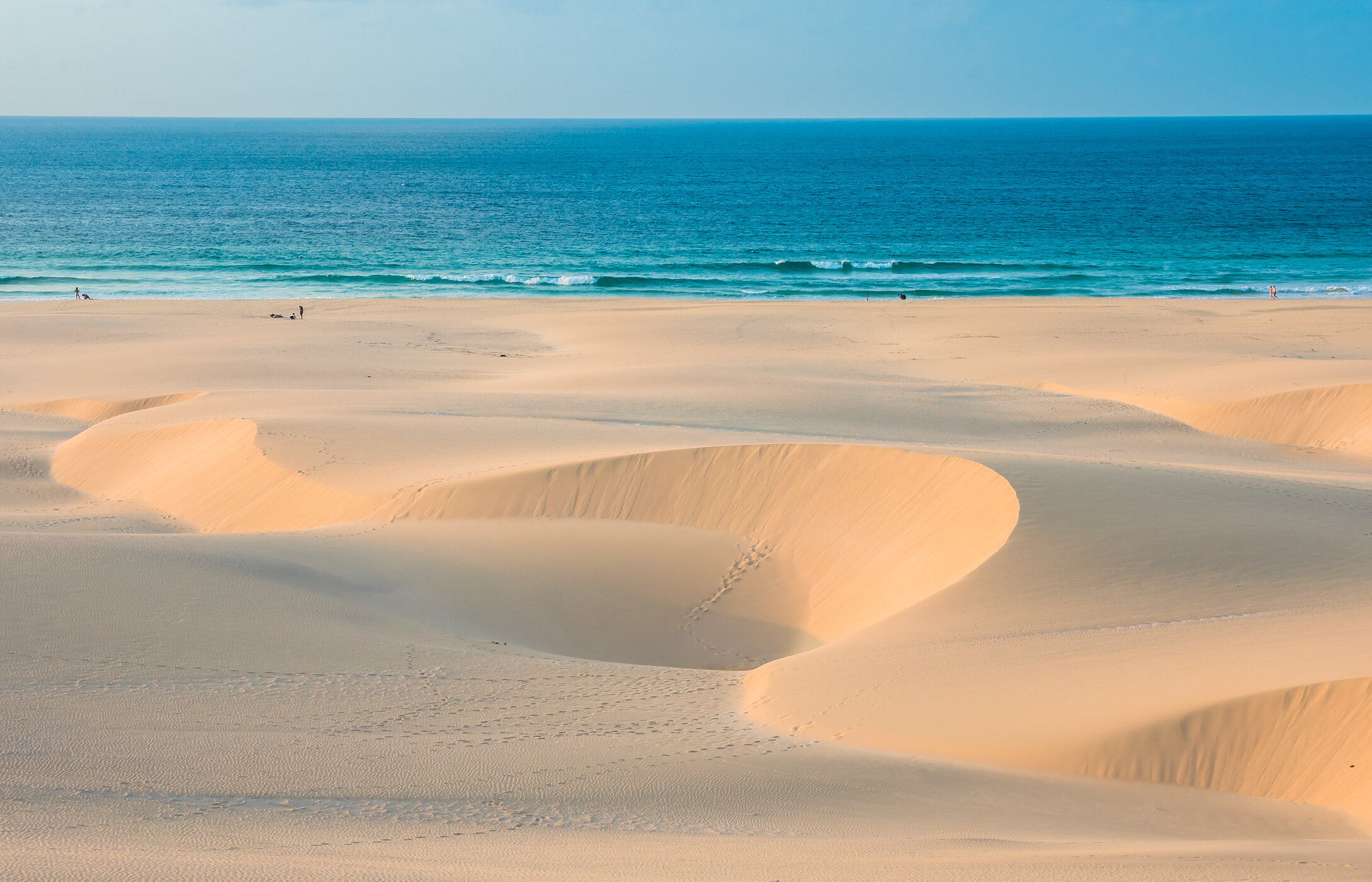 Vista panorámica de la playa de Chaves con dunas de arena esculpidas por el viento en contraste con el mar azul turquesa.