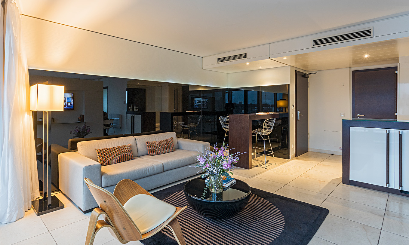 La Suite Panorámica del Pestana Berlin Tiergarten tiene sofá con lámpara, mesa de centro y un balcón con sillas