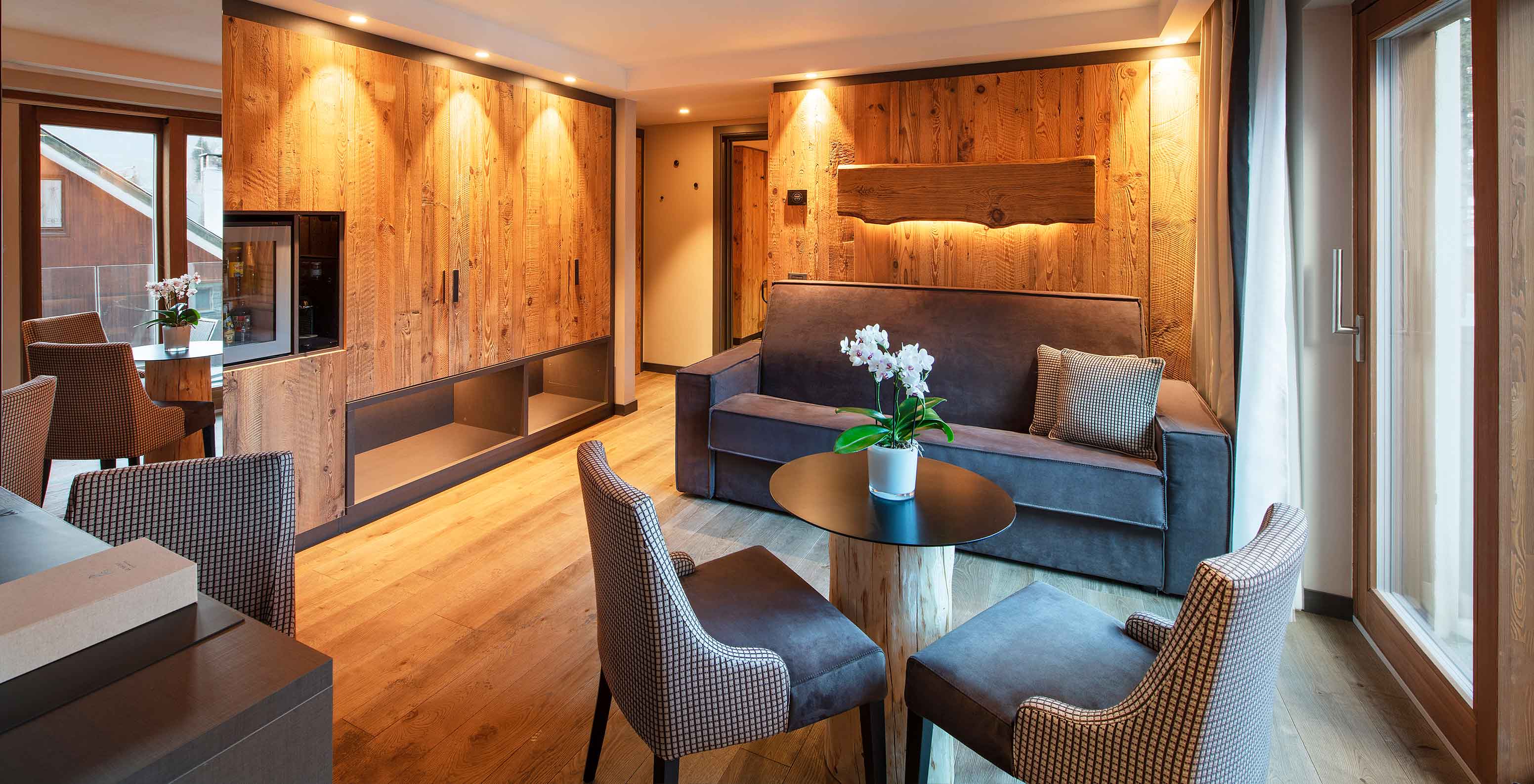 Le Massif Courmayeur, Hotel en los Alpes italianos, con salón de madera, sofá y mesa junto a ventanales