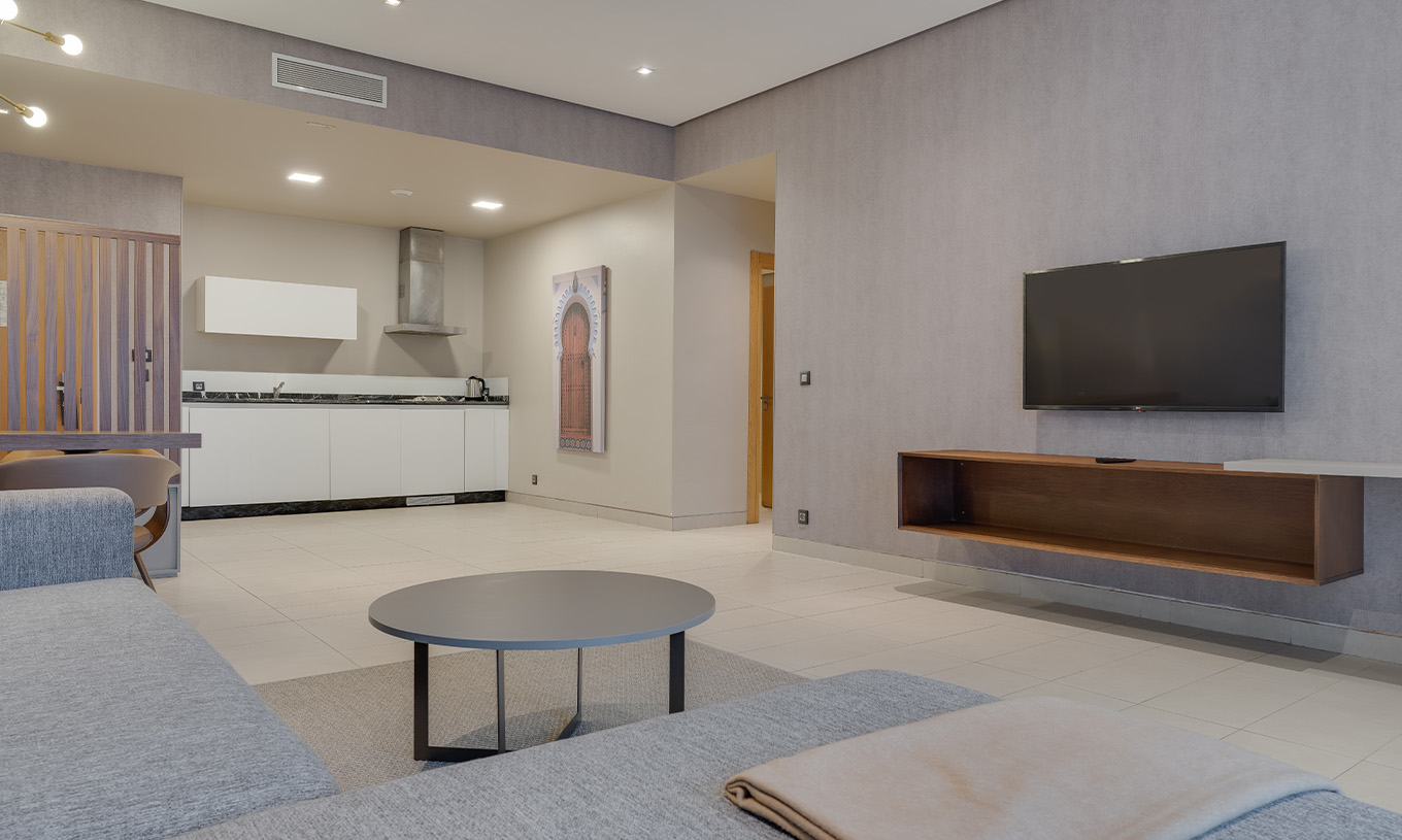 Suite Familiar con Vistas Laterales al Océano en Pestana Casablanca, salón con cocina y televisor mural