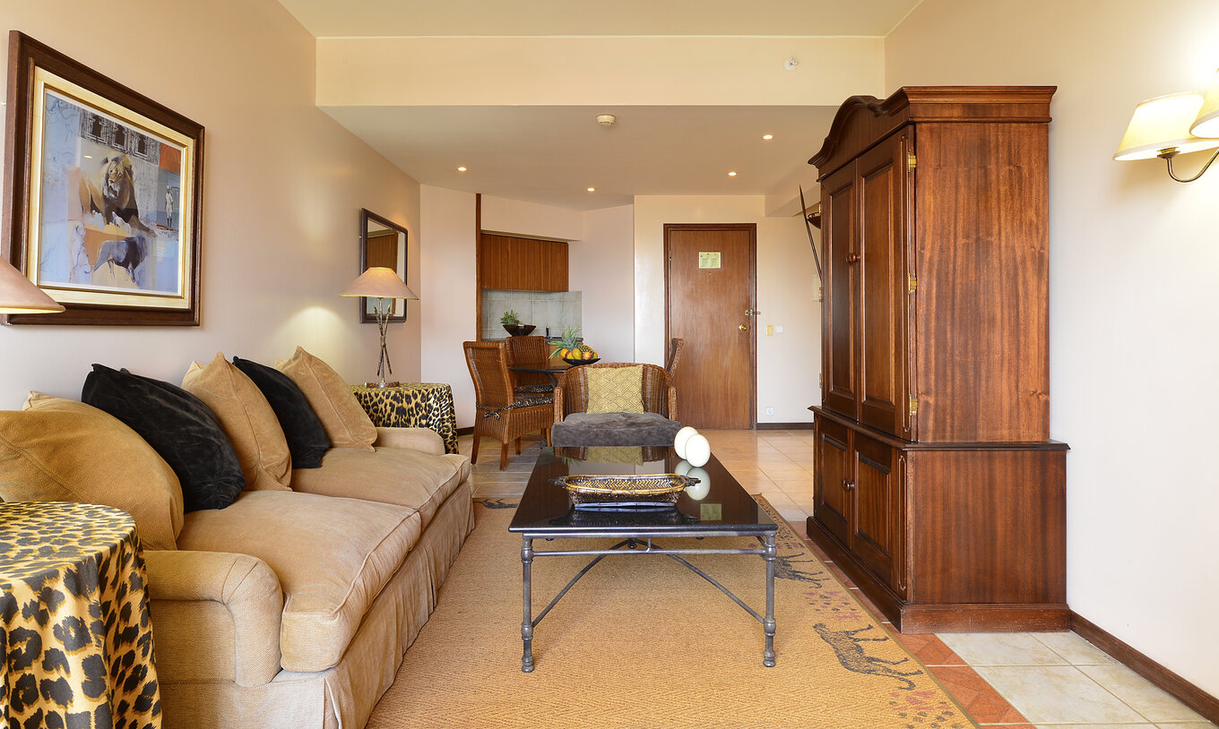 La Suite Luxo del Pestana Rovuma tiene una sala con un sofá blanco en beige y dos mesas con manteles de leopardo