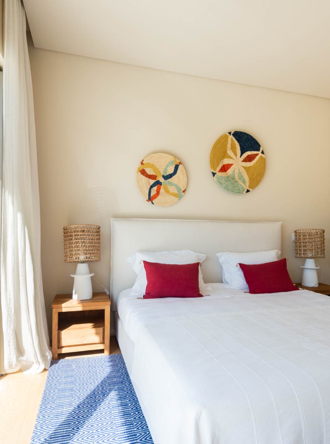 La villa exclusiva con piscina del Pestana Tróia Eco Resort tiene un dormitorio con cama, cojines rojos y alfombra azul