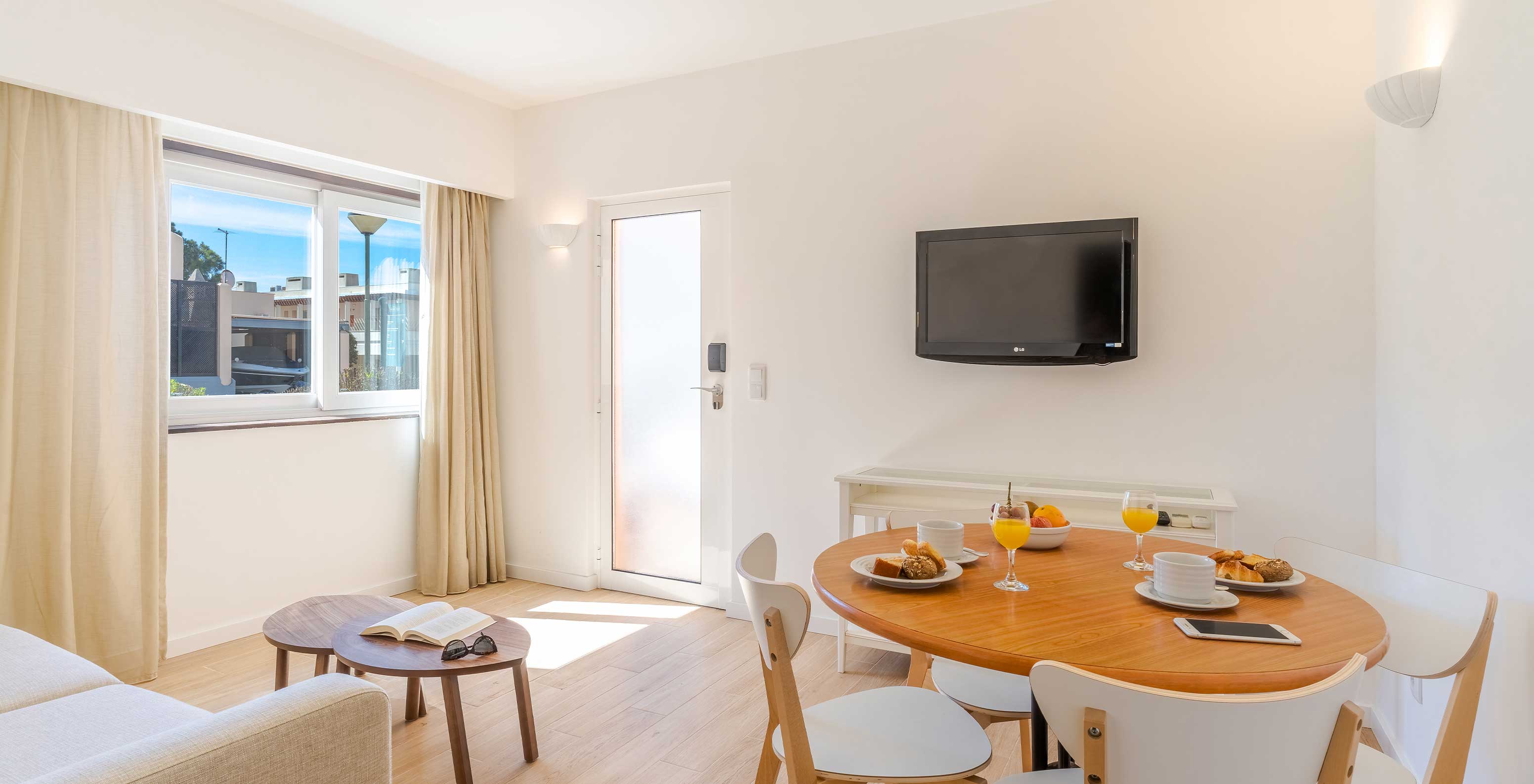 La Villa 1 Habitación Vista Jardín del Pestana Alvor Beach Villas tiene sala con televisión y mesa con sillas