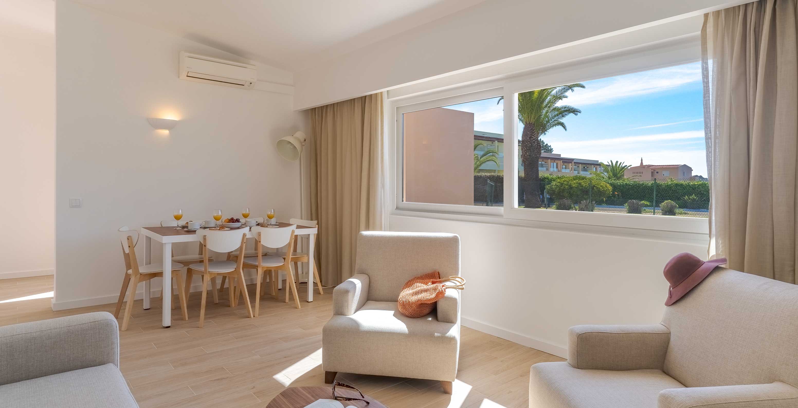 La Villa 3 Habitaciones Vista Jardín del Pestana Alvor Beach Villas tiene sala con poltronas, mesa y ventana con vista