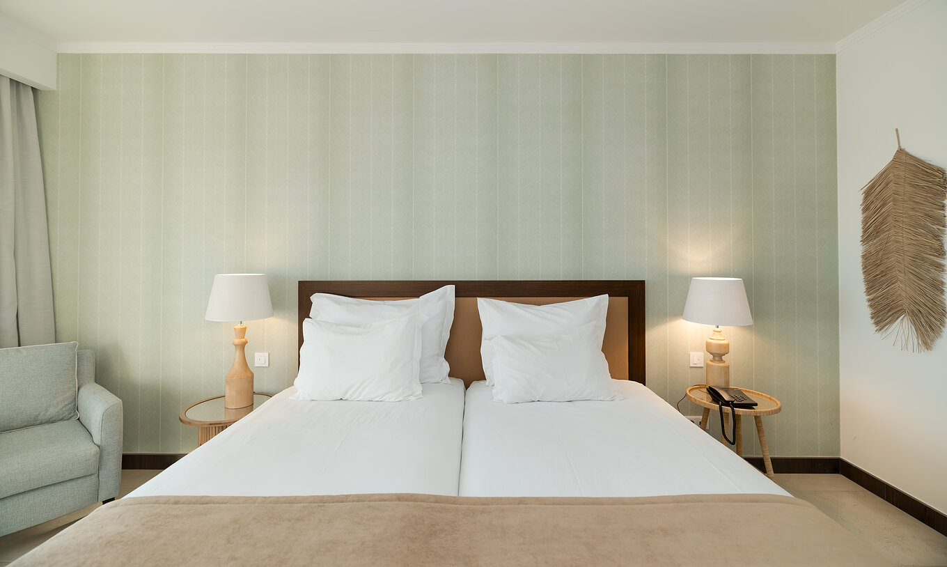 Estudio Vista Jardín en Pestana Alvor Beach Villas tiene dos camas con mesita y papel pintado en tonos verdes