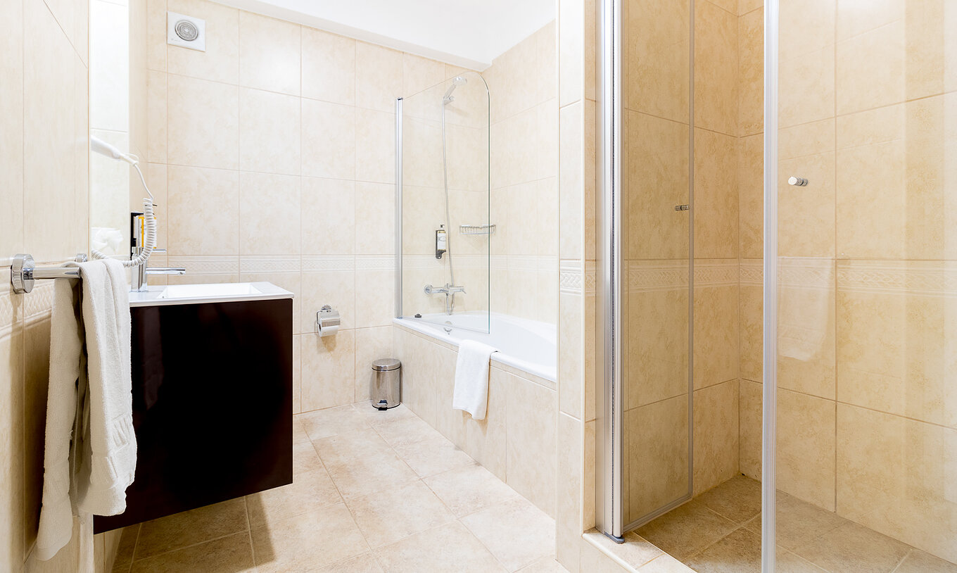 El apartamento de dos dormitorios en Pestana Gramacho tiene baño claro con bañera, ducha y lavabo moderno