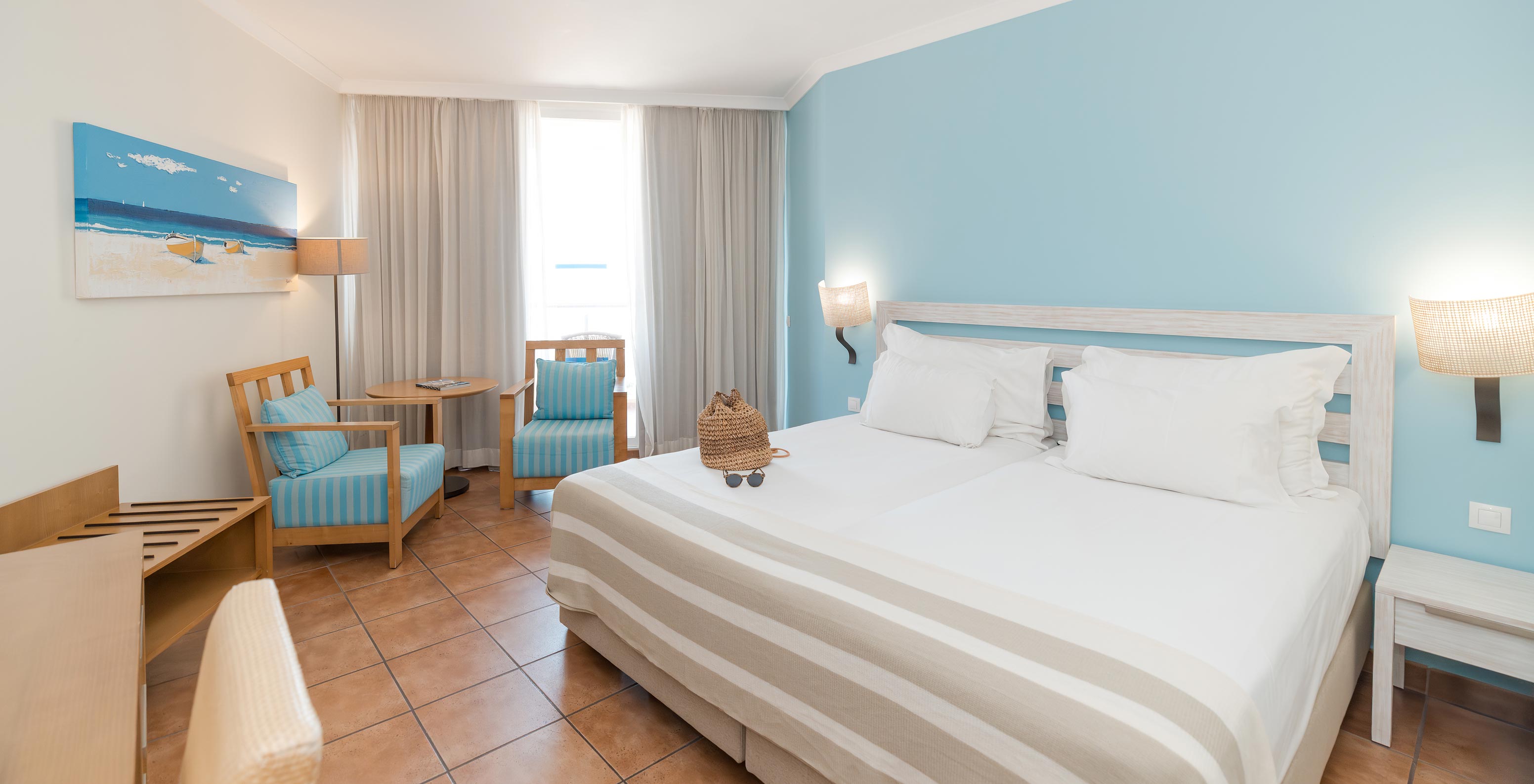 El Deluxe Vista Mar Lateral del Pestana Viking tiene dos camas, mesa de noche y dos sillones junto a la ventana