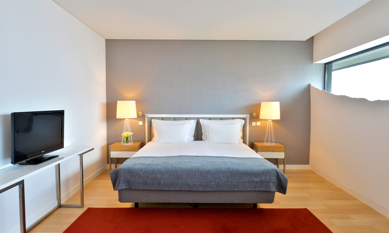 La Habitación Doble Superior del Pestana Cidadela Cascais tiene una cama doble, dos mesitas de noche y una alfombra roja