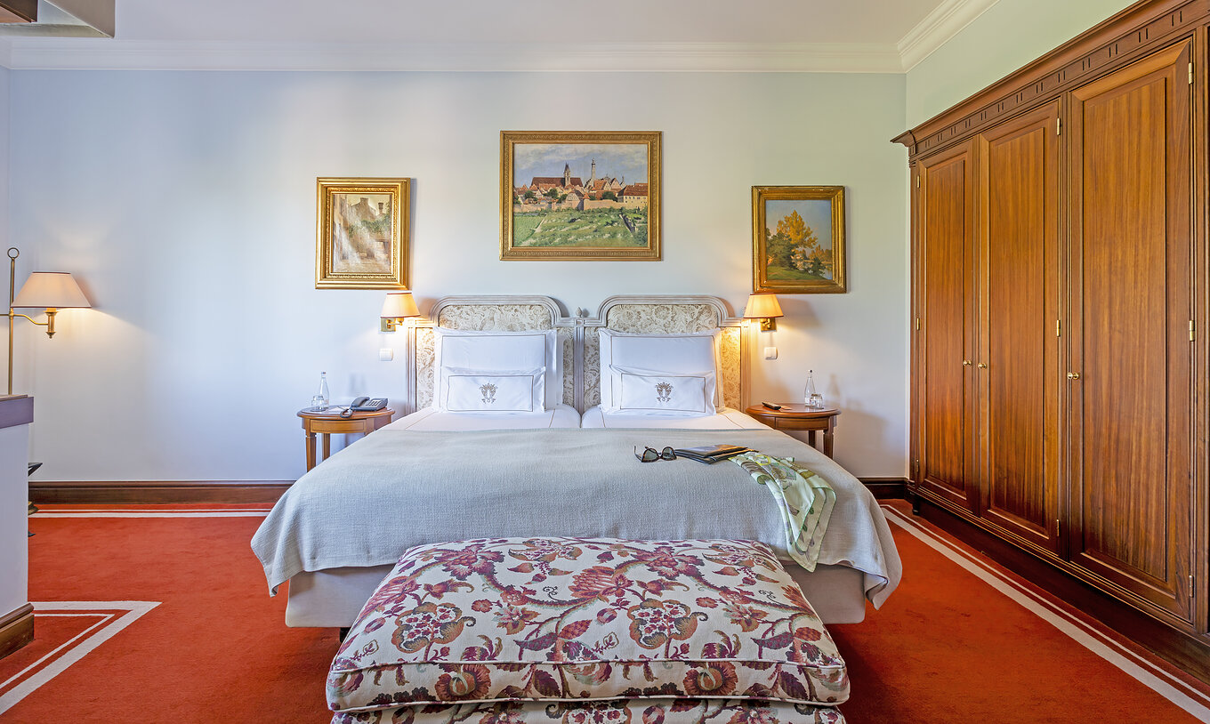 La Suite del Pestana Palace Lisboa tiene una cama doble con un banco a los pies de la cama y un armario grande