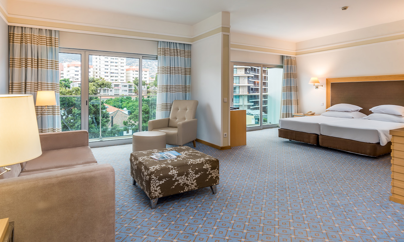 La habitación Doble Familiar del Pestana Carlton Madeira tiene zona de estar con sofás, cama de matrimonio y dos terrazas