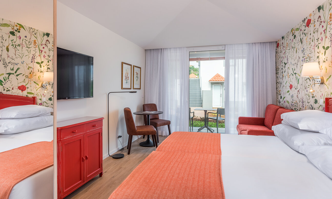 El Estudio - Vista mar del Pestana Quinta do Arco tiene dos camas juntas, televisión, sofá rojo y balcón con mesa y sillas