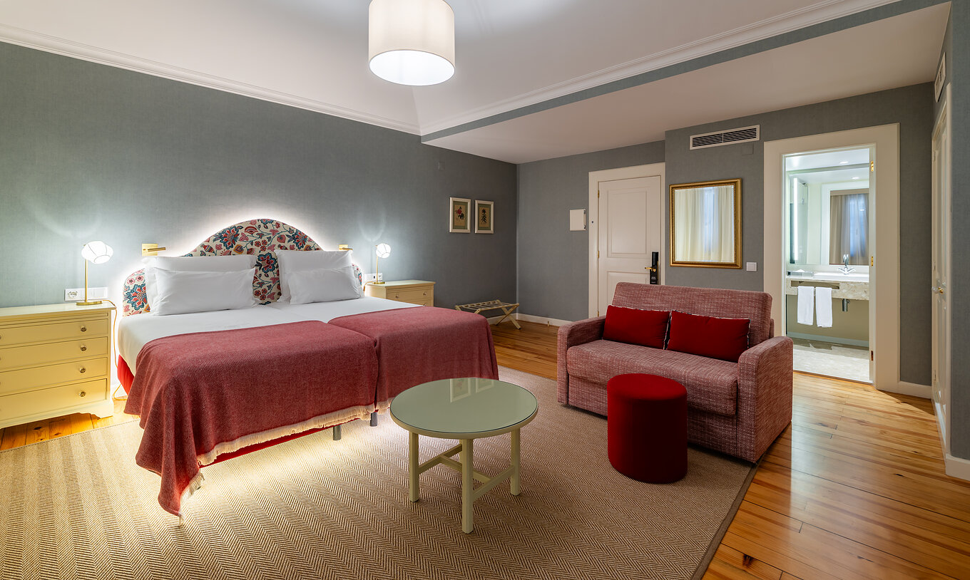 La Junior Suite Vista Mar Parcial del Pestana Quinta Perestrello tiene una cama doble, un sofá y un espejo.