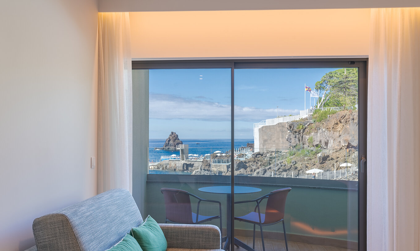 El Clásico Vista Mar Lateral del Pestana Vila Lido Madeira tiene un sofá al lado del balcón con vista lateral al mar