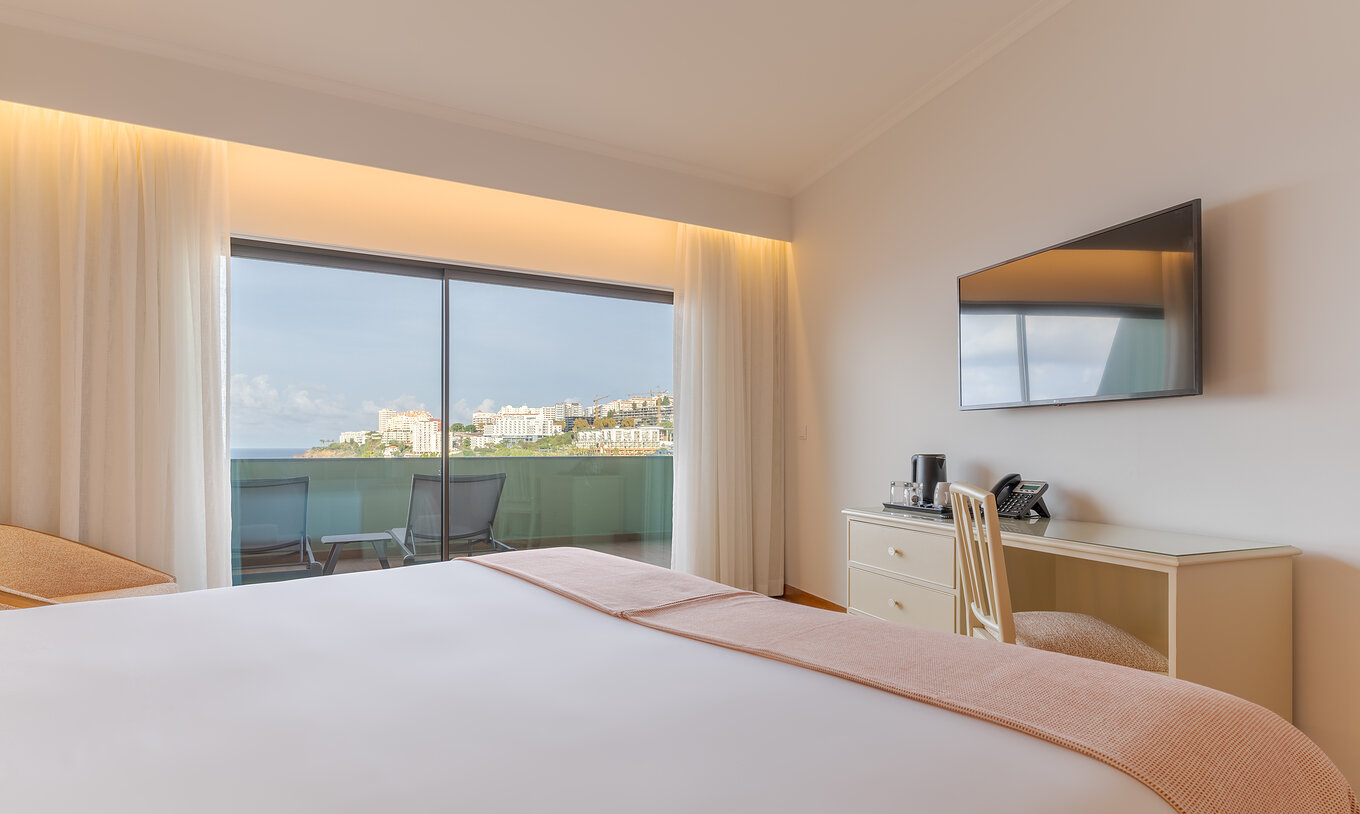 La Suite Superior Vista Mar Lateral del Pestana Vila Lido Madeira tiene una televisión colgada en la pared y un balcón