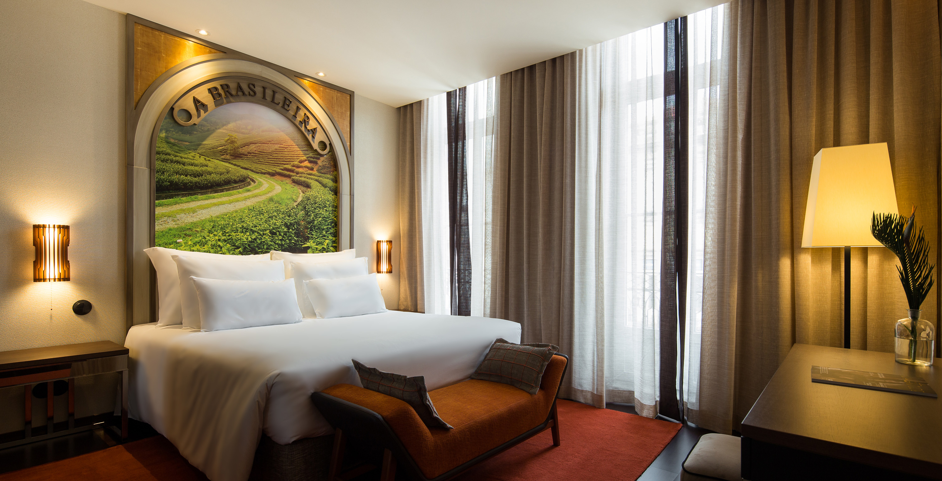 El Deluxe Superior del Pestana Porto - A Brasileira tiene una cama con un mural temático en la cabecera y un banco al fondo