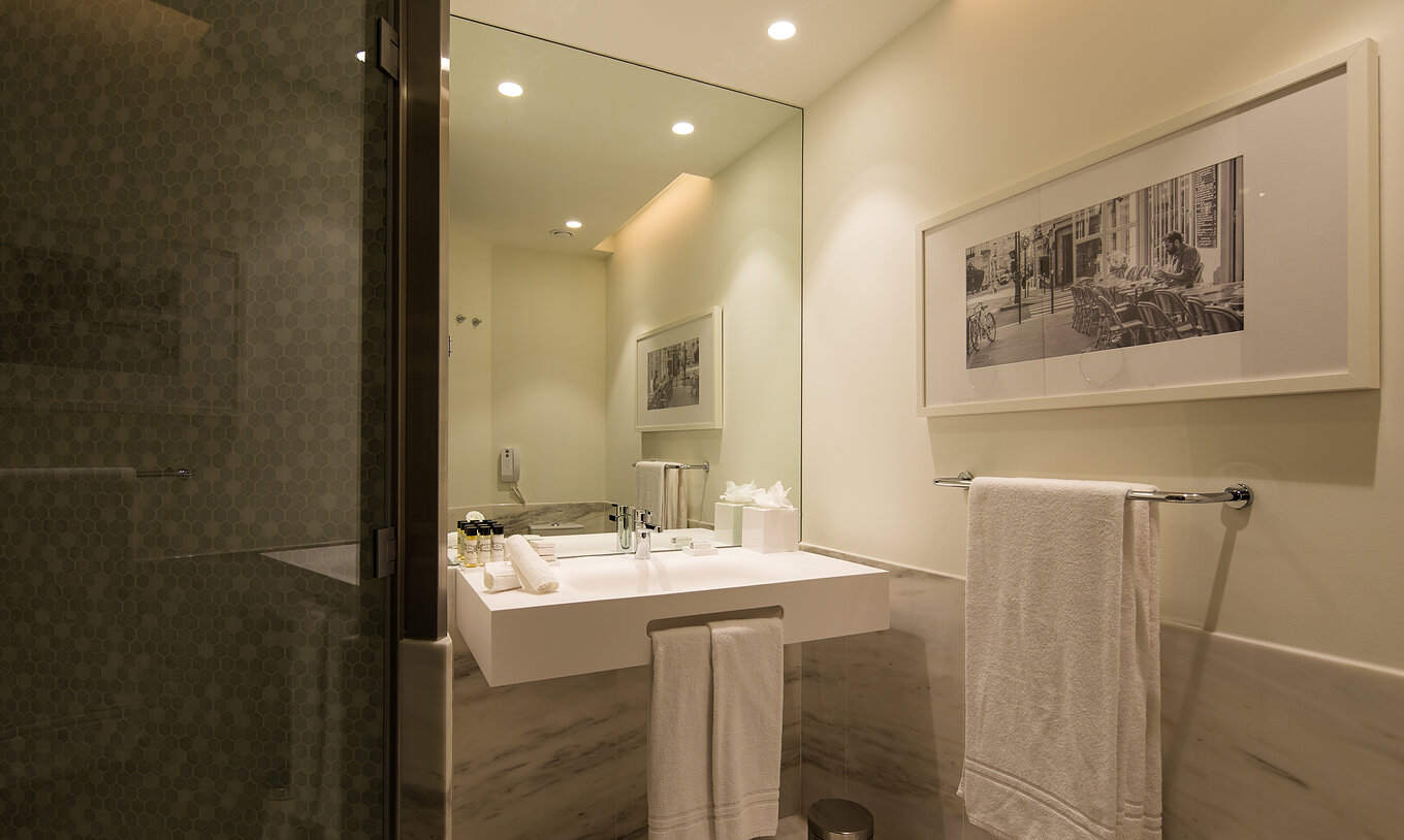 Habitación Premium Origin en Pestana Porto - A Brasileira con baño moderno, espejo amplio y ducha acristalada