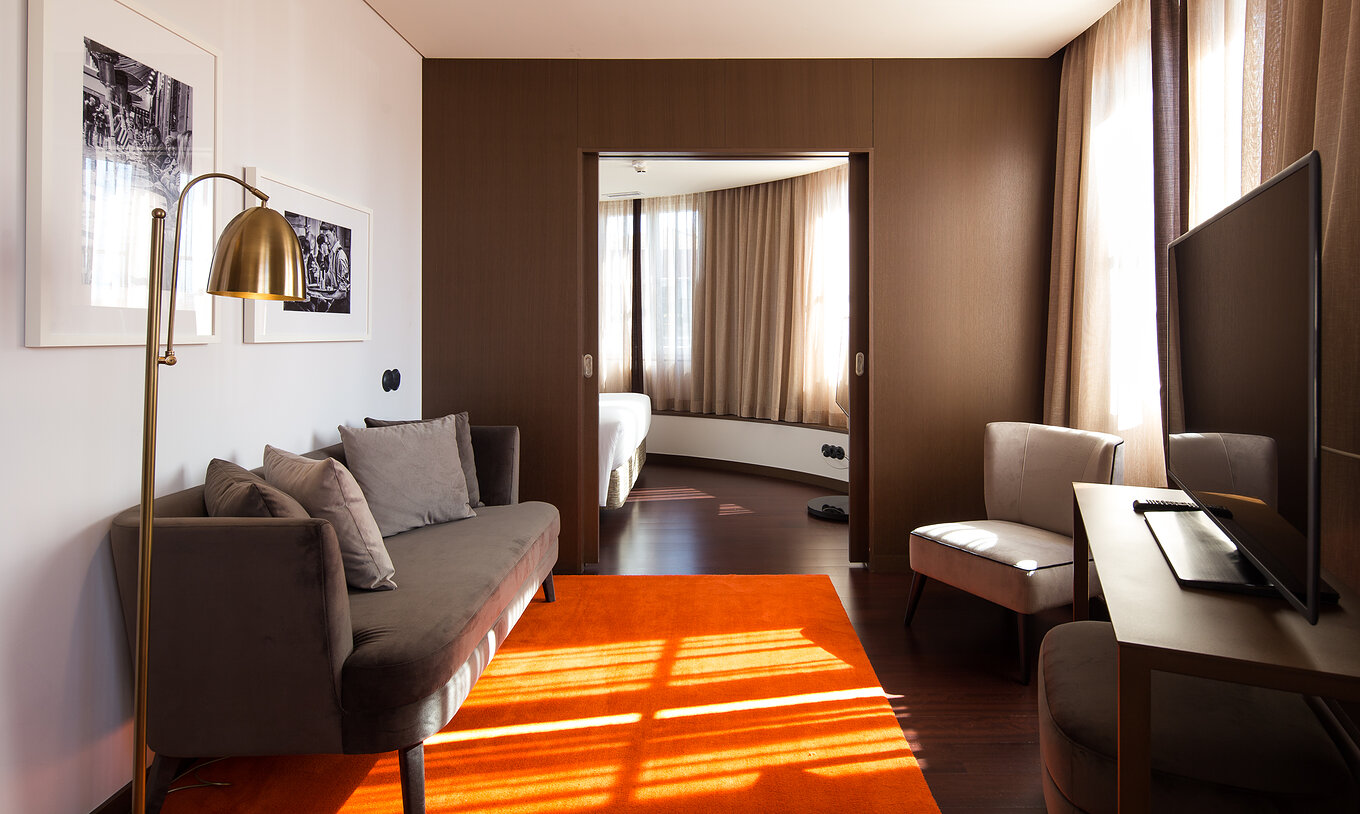 Suite A Brasileira en Pestana Porto - A Brasileira con sofá gris, sillón claro y dormitorio iluminado