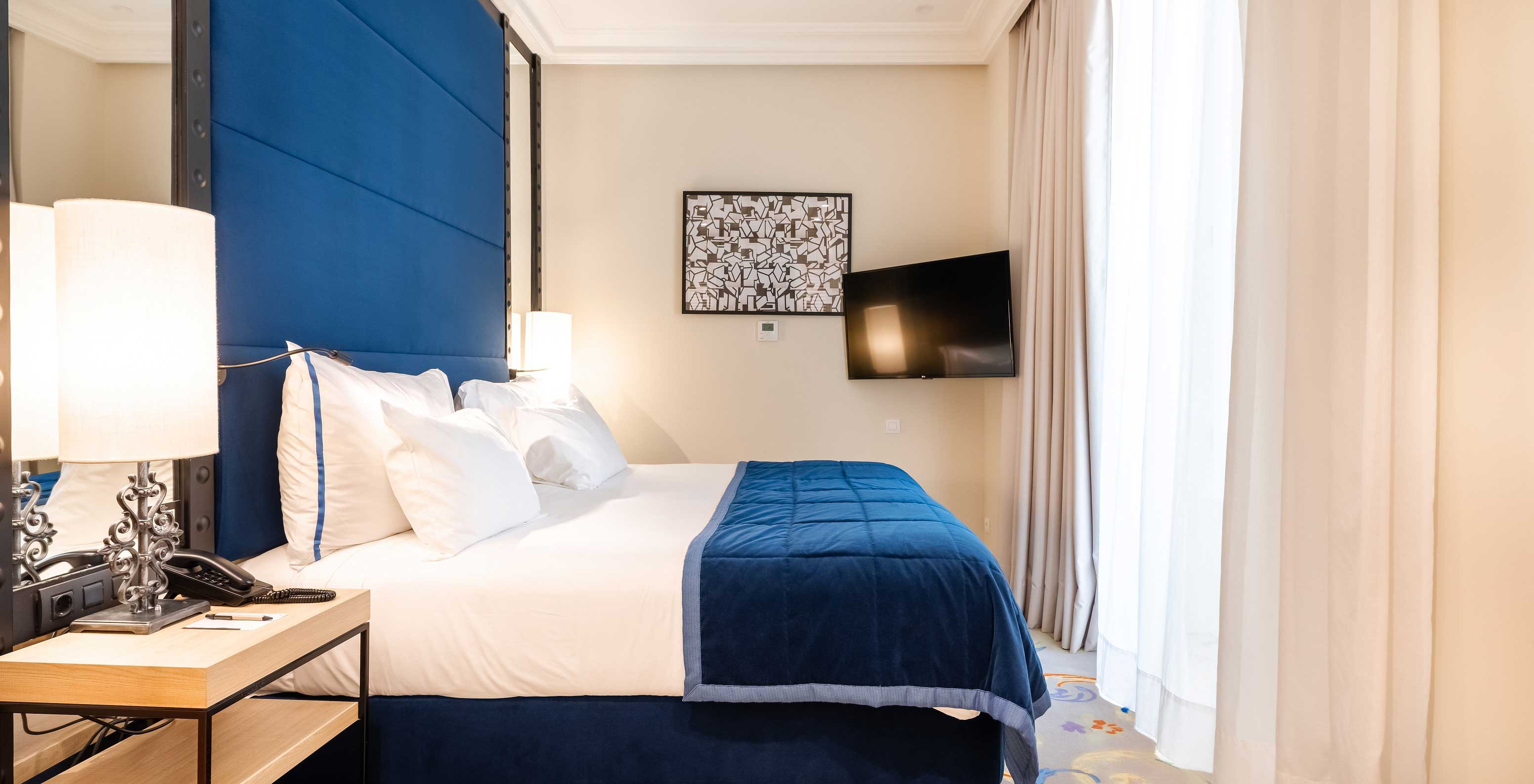 La habitación Superior del Pestana Collection Plaza Mayor tiene una cama doble, un cabecero azul, una televisión y espejos