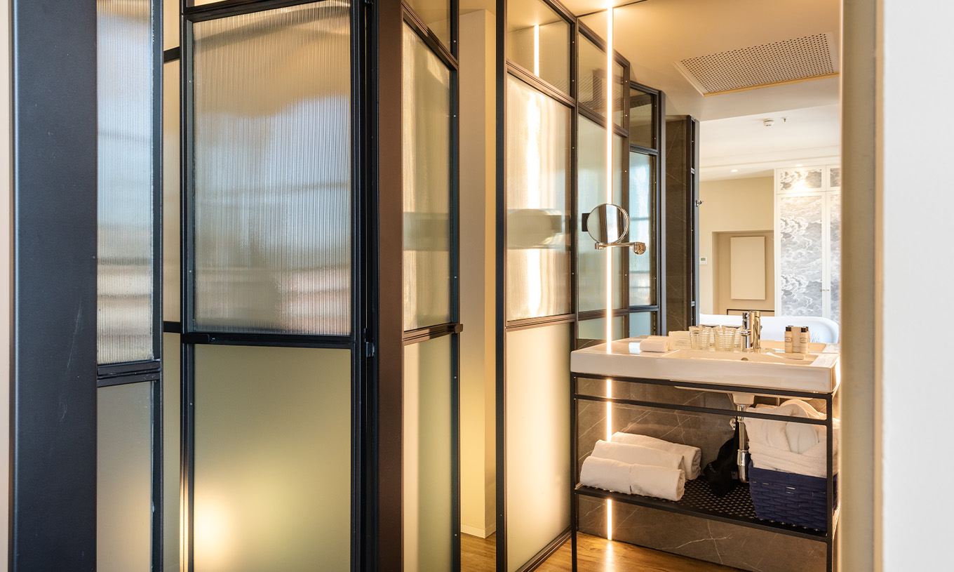 El Deluxe Grand Plaza Mayor del Pestana Plaza Mayor Madrid tiene un baño con lavabo con espejo y toallas