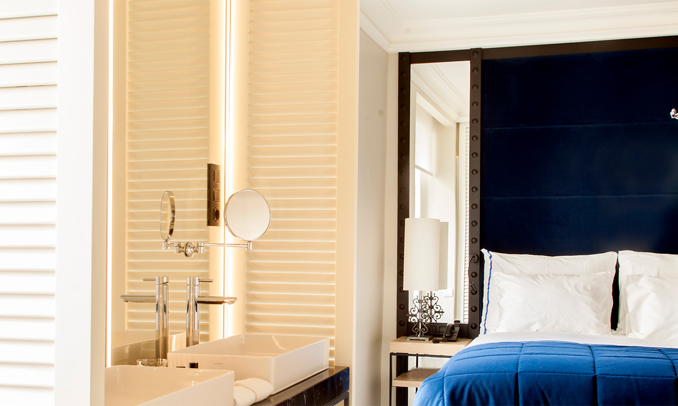 El Cuarto Superior del Pestana Plaza Mayor Madrid tiene una cama de casal con cabecera azul con espejo y un lavabo